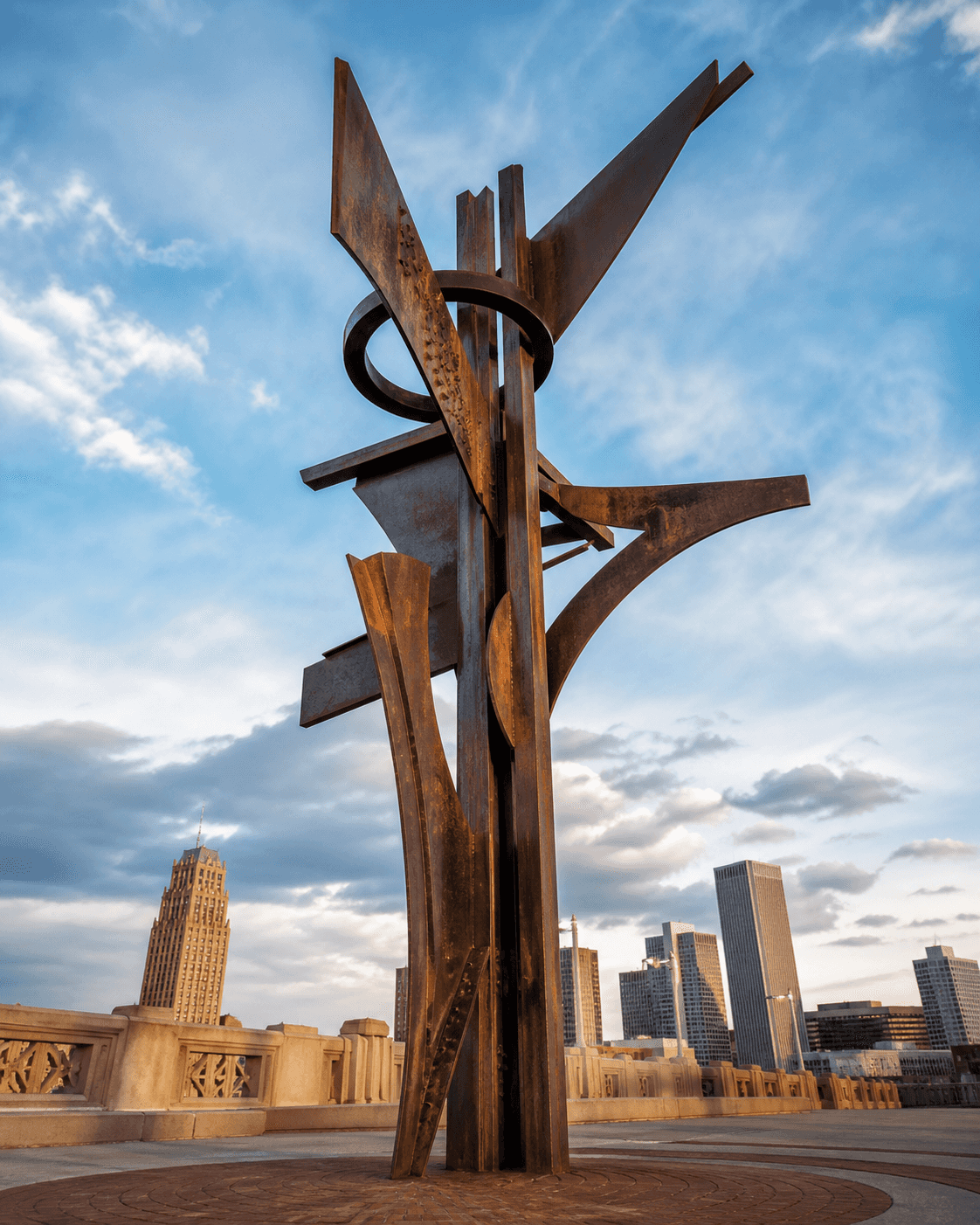 Weathered monumental steel public art against the Tulsa sky.